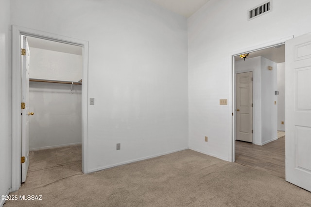 unfurnished bedroom featuring a walk in closet, visible vents, and carpet floors