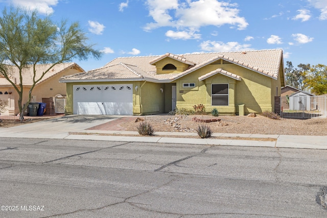 view of front facade with fence, a tiled roof, concrete driveway, stucco siding, and a garage