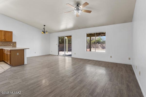 unfurnished living room with lofted ceiling, light wood-style flooring, and ceiling fan with notable chandelier