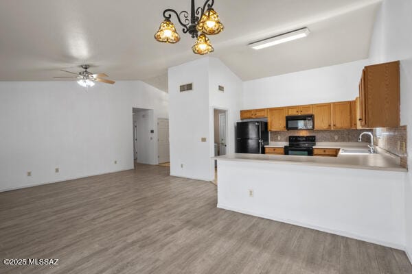 kitchen featuring open floor plan, brown cabinets, black appliances, and a sink