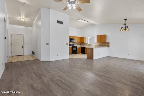 kitchen featuring wood finished floors, visible vents, a peninsula, black appliances, and open floor plan