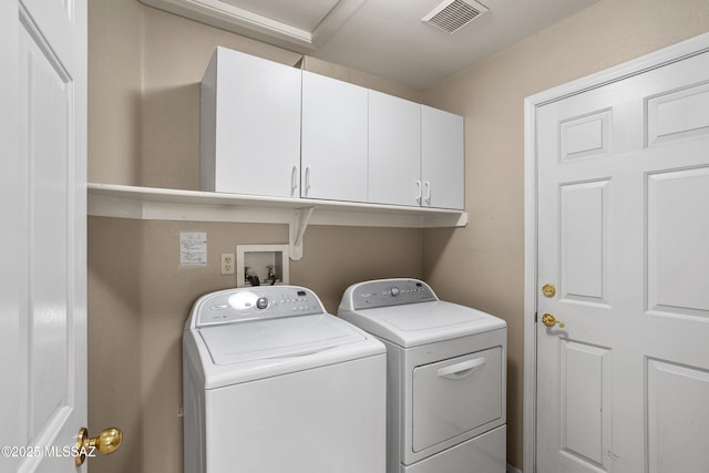 laundry room featuring washing machine and clothes dryer, visible vents, and cabinet space