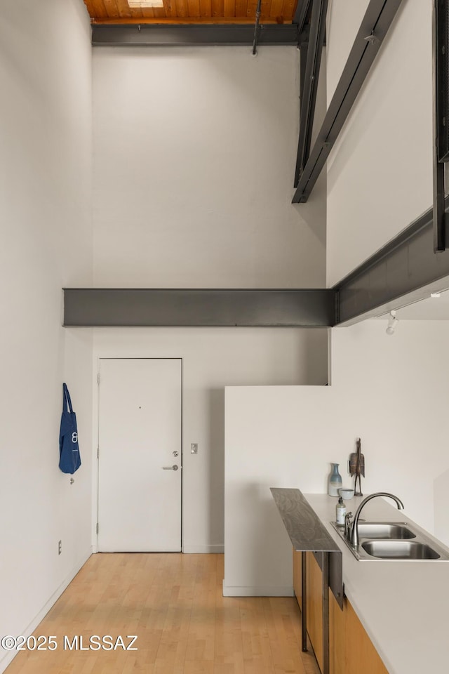 kitchen featuring light countertops, a high ceiling, light wood-style floors, and a sink