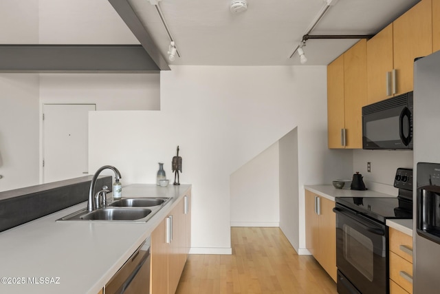 kitchen with black appliances, light countertops, light brown cabinets, and a sink