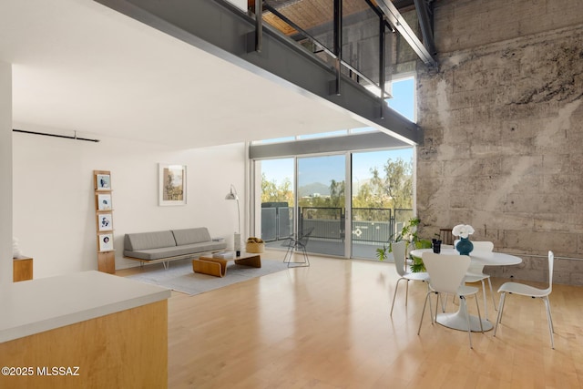 unfurnished dining area with a high ceiling, a healthy amount of sunlight, and wood finished floors