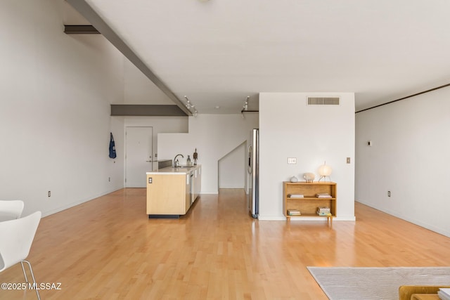 kitchen featuring visible vents, light wood finished floors, a sink, freestanding refrigerator, and light countertops