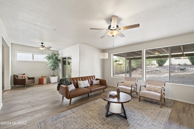 living area with baseboards, a textured ceiling, ceiling fan, and wood finished floors