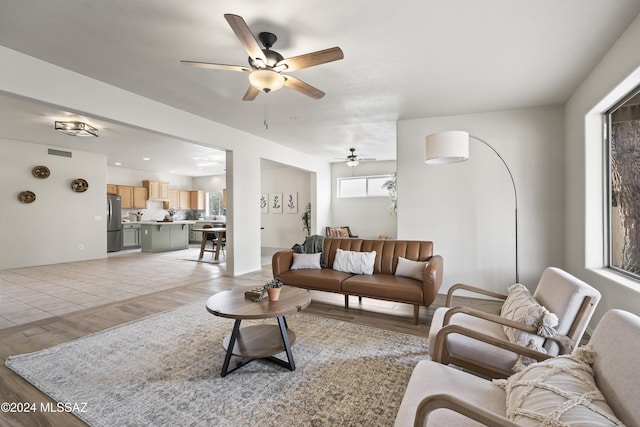 living room with light wood-style flooring, a ceiling fan, and visible vents