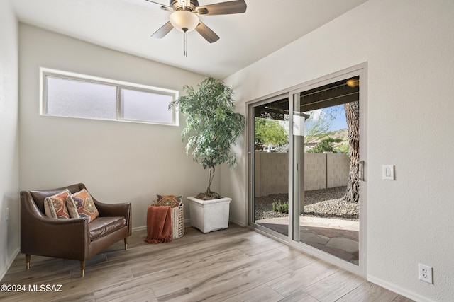 living area with a wealth of natural light, baseboards, ceiling fan, and wood finished floors