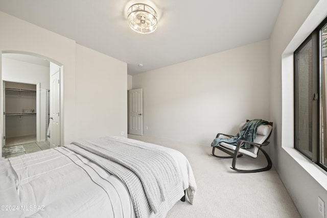 bedroom with arched walkways and light colored carpet