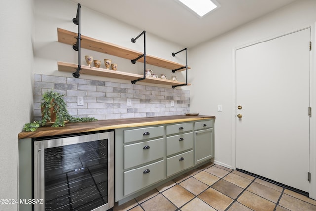 bar featuring wine cooler, decorative backsplash, a dry bar, and light tile patterned flooring