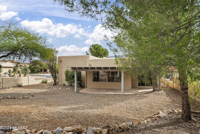 rear view of property with stucco siding, a patio, and fence