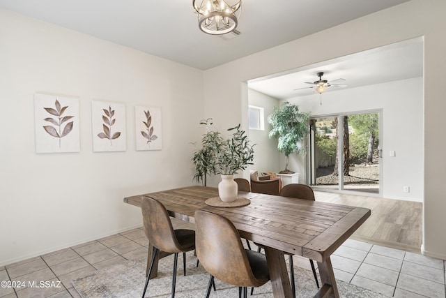 dining area featuring light tile patterned flooring, visible vents, ceiling fan with notable chandelier, and baseboards