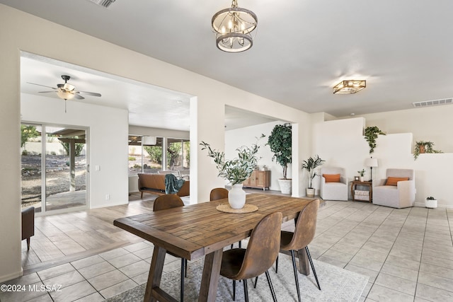 dining space with light tile patterned floors, visible vents, baseboards, and ceiling fan with notable chandelier