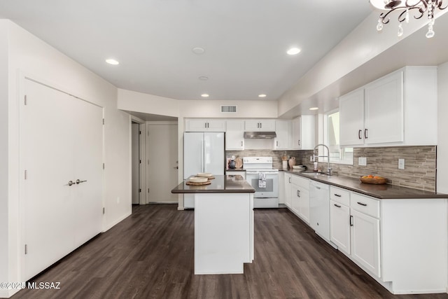 kitchen with a sink, visible vents, white appliances, and dark countertops