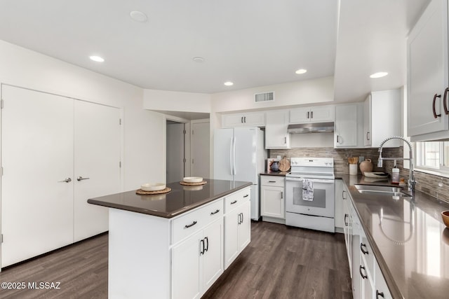 kitchen with visible vents, dark wood-type flooring, a sink, under cabinet range hood, and white appliances