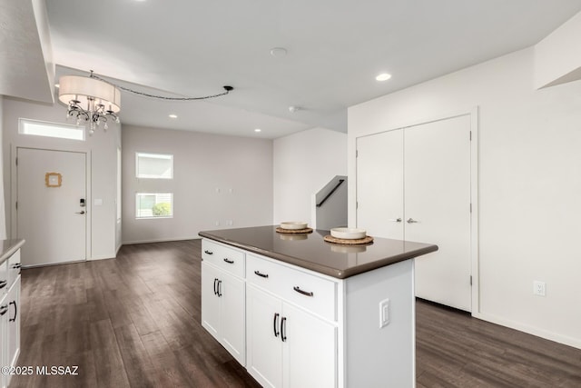 kitchen with dark countertops, a center island, dark wood-type flooring, and an inviting chandelier