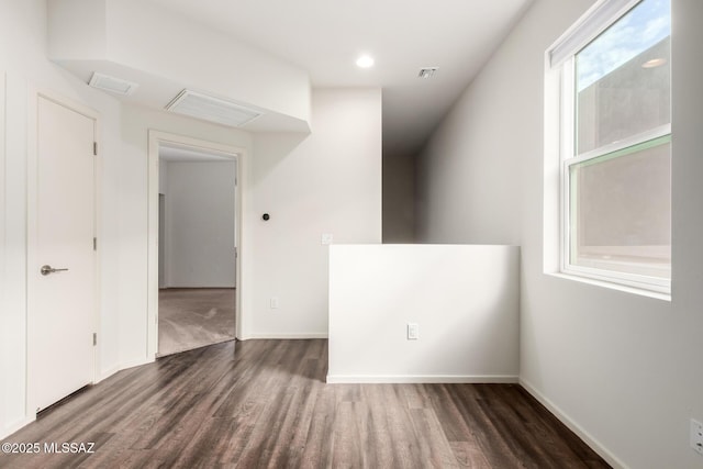 empty room featuring wood finished floors, visible vents, and baseboards