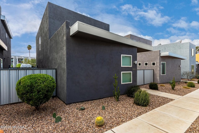 view of property exterior with stucco siding and fence