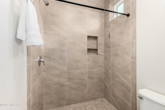 bathroom featuring tiled shower and toilet