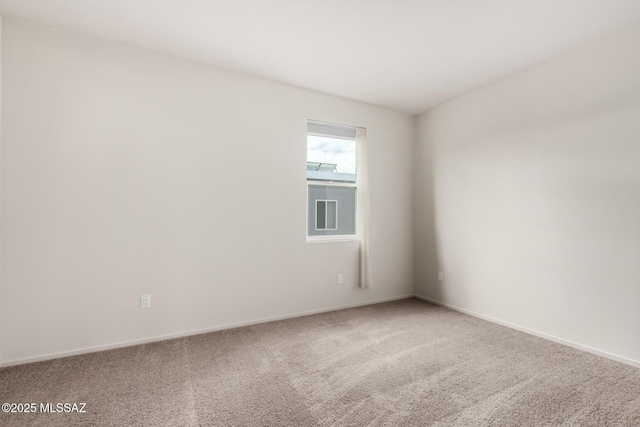 spare room with baseboards and carpet flooring