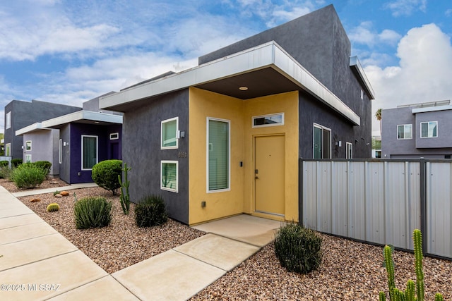 modern home featuring stucco siding and fence