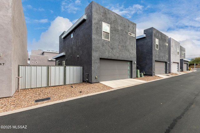 view of side of property with stucco siding, concrete driveway, and fence