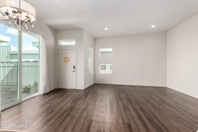 foyer entrance with a notable chandelier, a healthy amount of sunlight, and dark wood-style floors