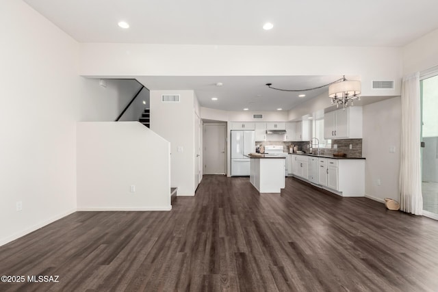 kitchen with dark countertops, visible vents, freestanding refrigerator, and dark wood-style flooring