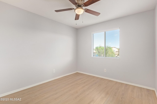 spare room featuring light wood-type flooring, baseboards, and a ceiling fan