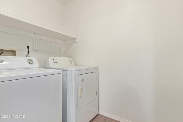 laundry room with laundry area, washing machine and dryer, light wood-style floors, and baseboards