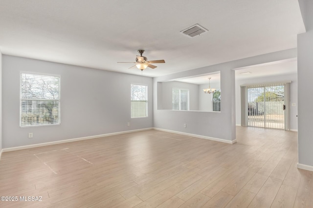 unfurnished room with ceiling fan with notable chandelier, light wood-style floors, visible vents, and baseboards