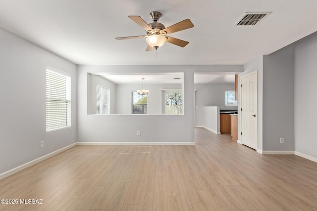 unfurnished living room featuring visible vents, ceiling fan with notable chandelier, baseboards, and light wood-style floors