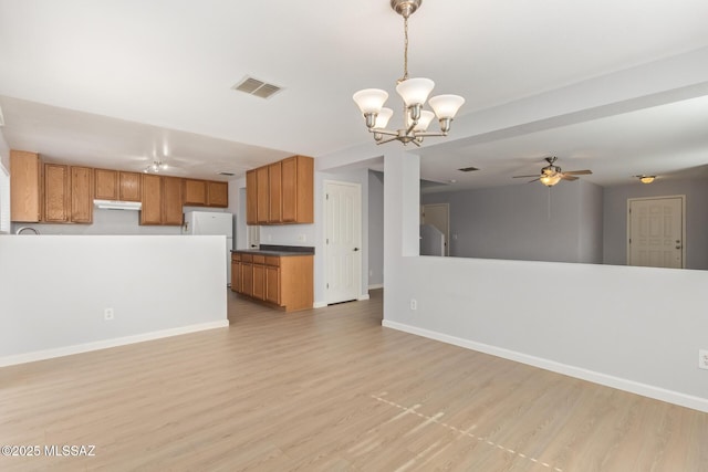 unfurnished living room featuring ceiling fan with notable chandelier, visible vents, light wood-style floors, and baseboards