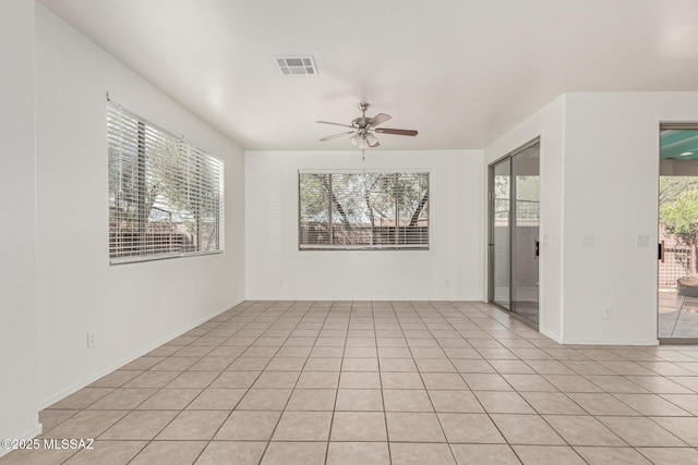 empty room featuring light tile patterned floors, visible vents, plenty of natural light, and ceiling fan