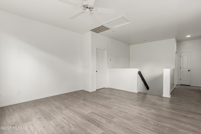 empty room with visible vents, baseboards, attic access, and wood finished floors