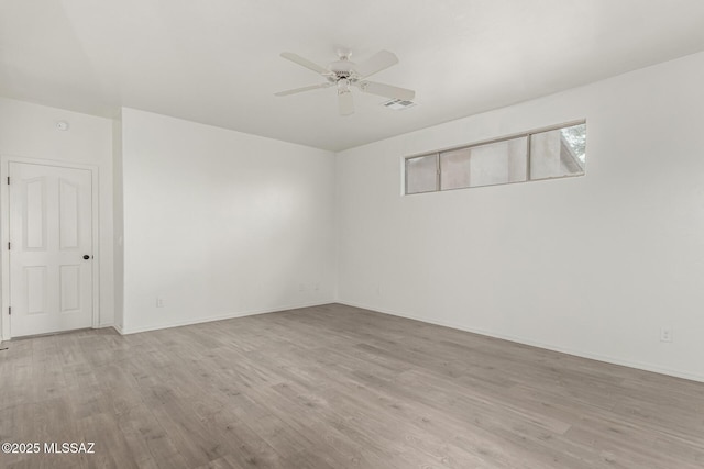 unfurnished room with ceiling fan, visible vents, baseboards, and wood finished floors