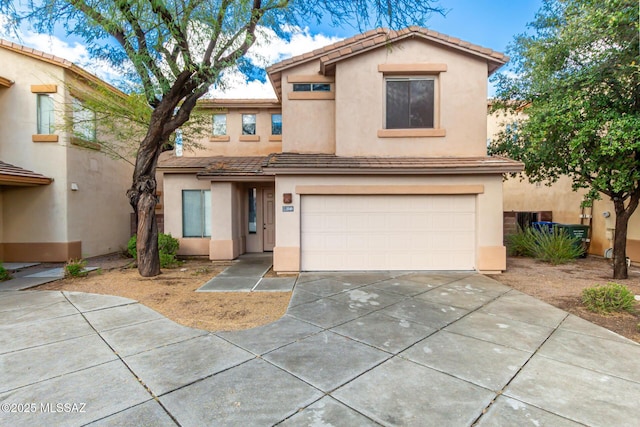 view of front of house with a tile roof, stucco siding, an attached garage, and concrete driveway