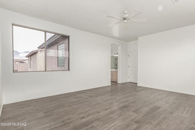 spare room featuring baseboards, ceiling fan, and wood finished floors