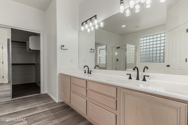 bathroom with double vanity, wood finished floors, a stall shower, and a sink