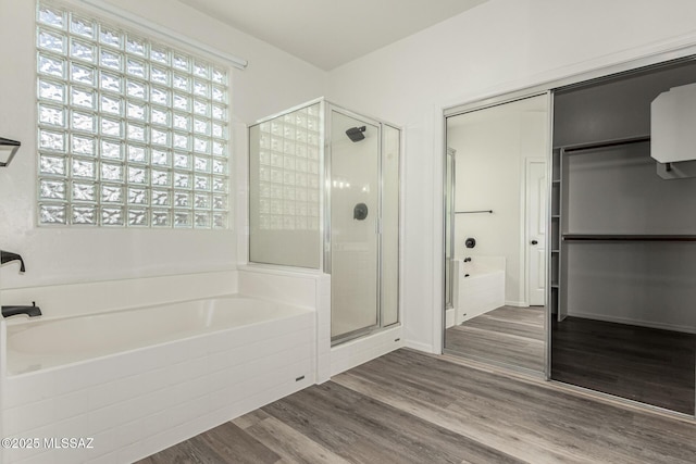 full bathroom featuring a garden tub, wood finished floors, a stall shower, and a closet