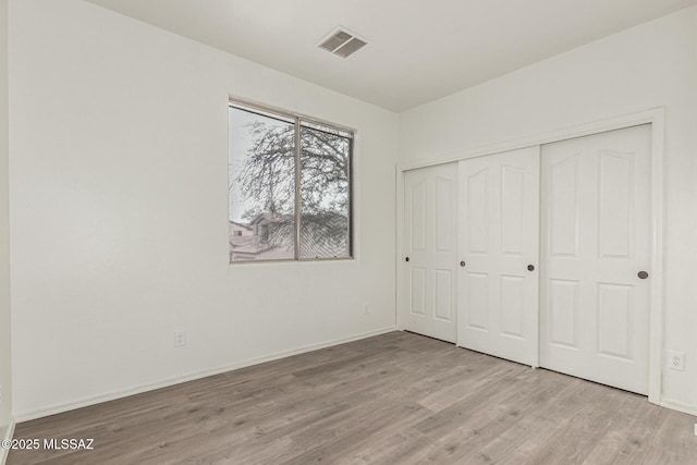 unfurnished bedroom with visible vents, baseboards, light wood-style floors, and a closet