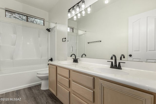 full bathroom featuring double vanity, toilet, wood finished floors, and a sink