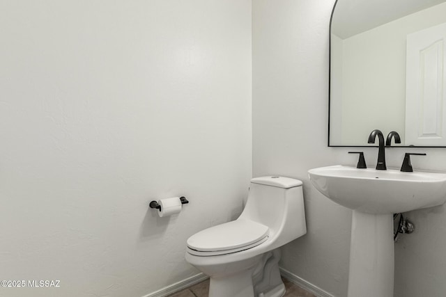 half bath featuring toilet and baseboards