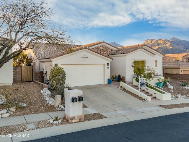 view of front of house with fence, a tile roof, concrete driveway, stucco siding, and an attached garage