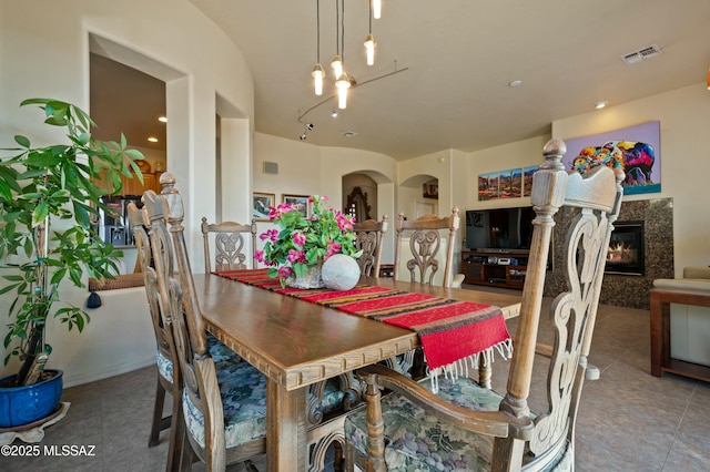 dining room with tile patterned flooring, visible vents, and a high end fireplace