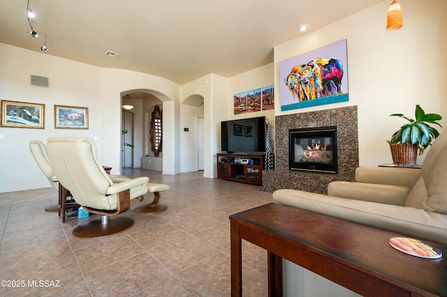 living area with arched walkways, visible vents, tile patterned floors, and a premium fireplace