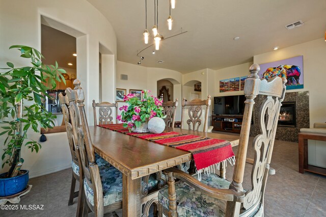 dining space with tile patterned flooring, visible vents, and a fireplace