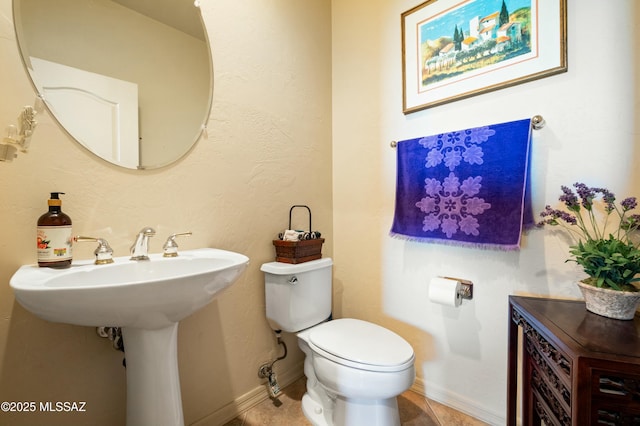 half bath with tile patterned floors, baseboards, and toilet