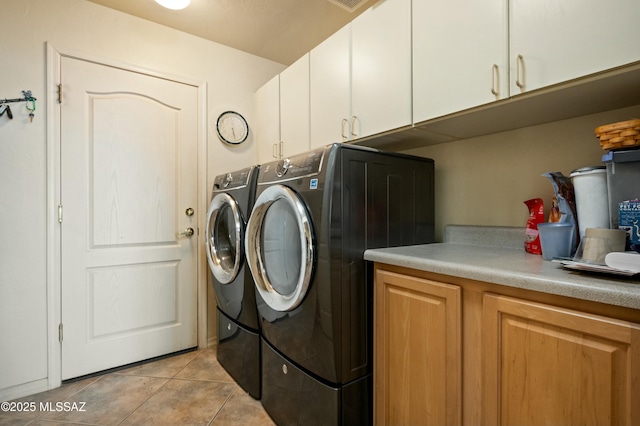 clothes washing area featuring light tile patterned flooring, cabinet space, and washing machine and clothes dryer